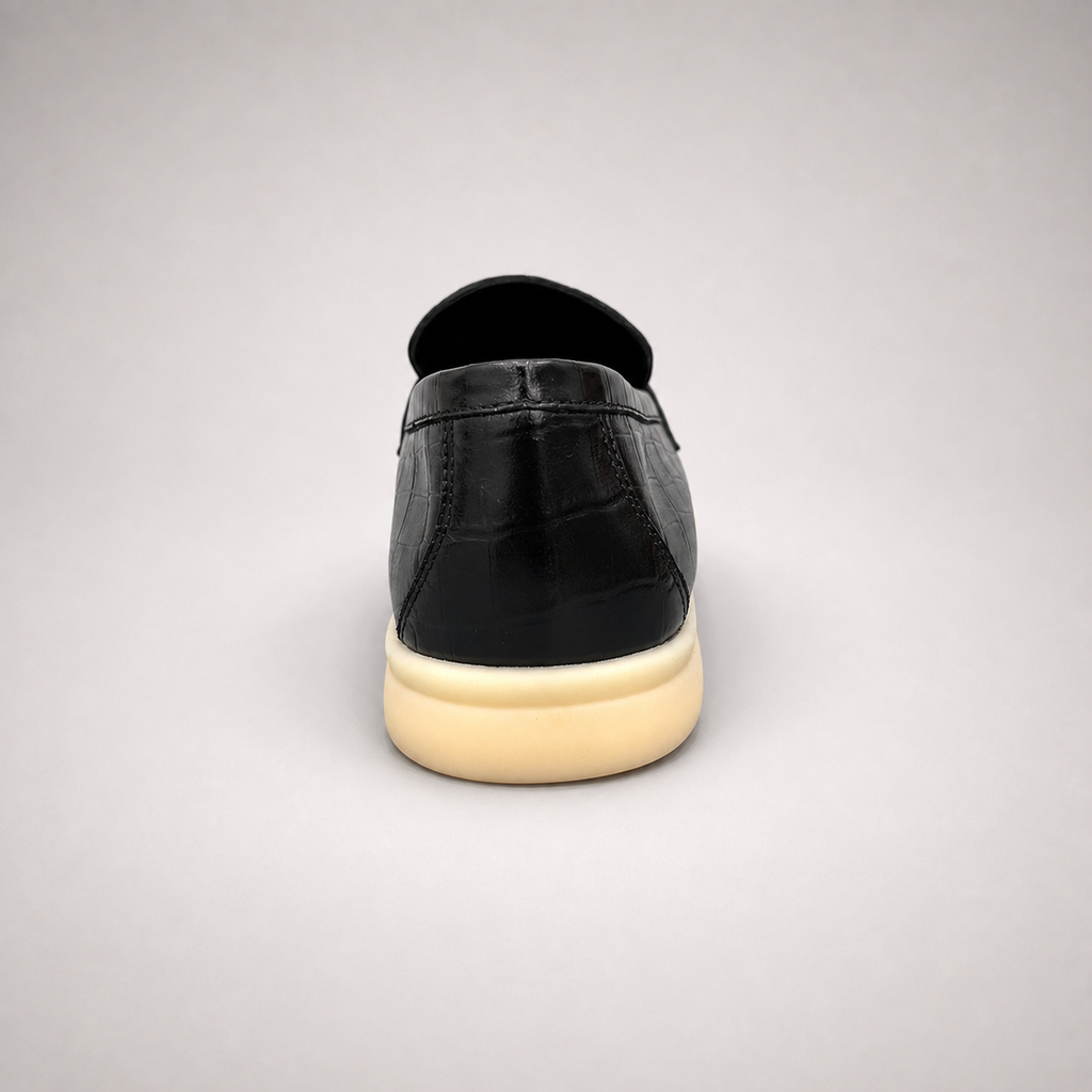Black loafer rear view showing a crocodile-pattern embossed upper and metal accent
