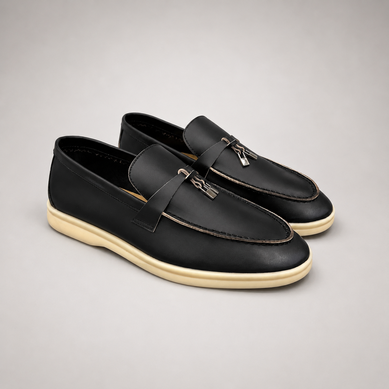Black loafer pair three-quarter view showing a metal accent across the vamp
