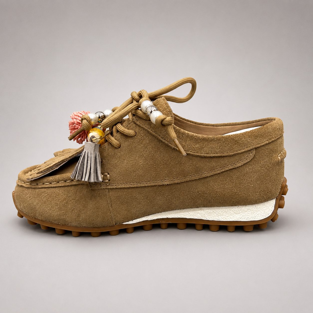 Tan moccasin sneaker opposite side profile showing fringe and tassel details over the laces