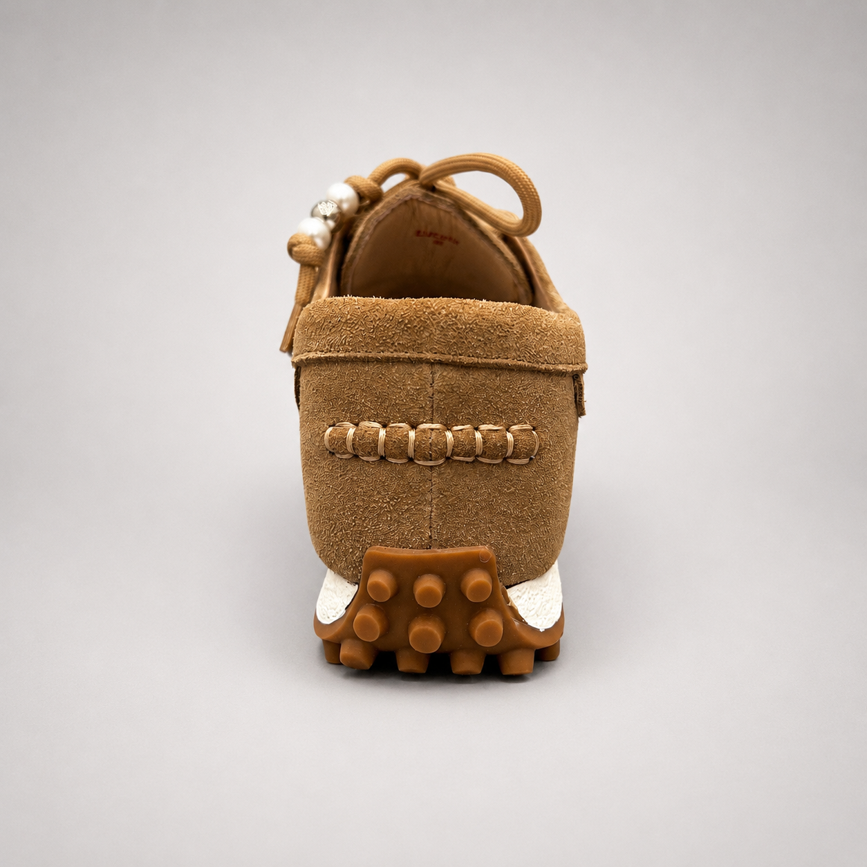 Tan moccasin sneaker rear view showing fringe and tassel details over the laces