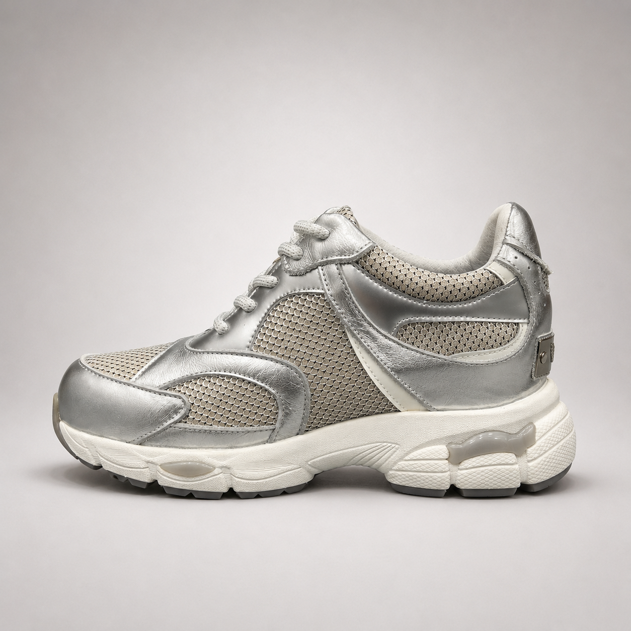 Silver sneaker side profile showing a panelled lace-up upper