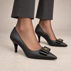 Black pointed-toe bow-ornament leather pumps worn with charcoal trousers
