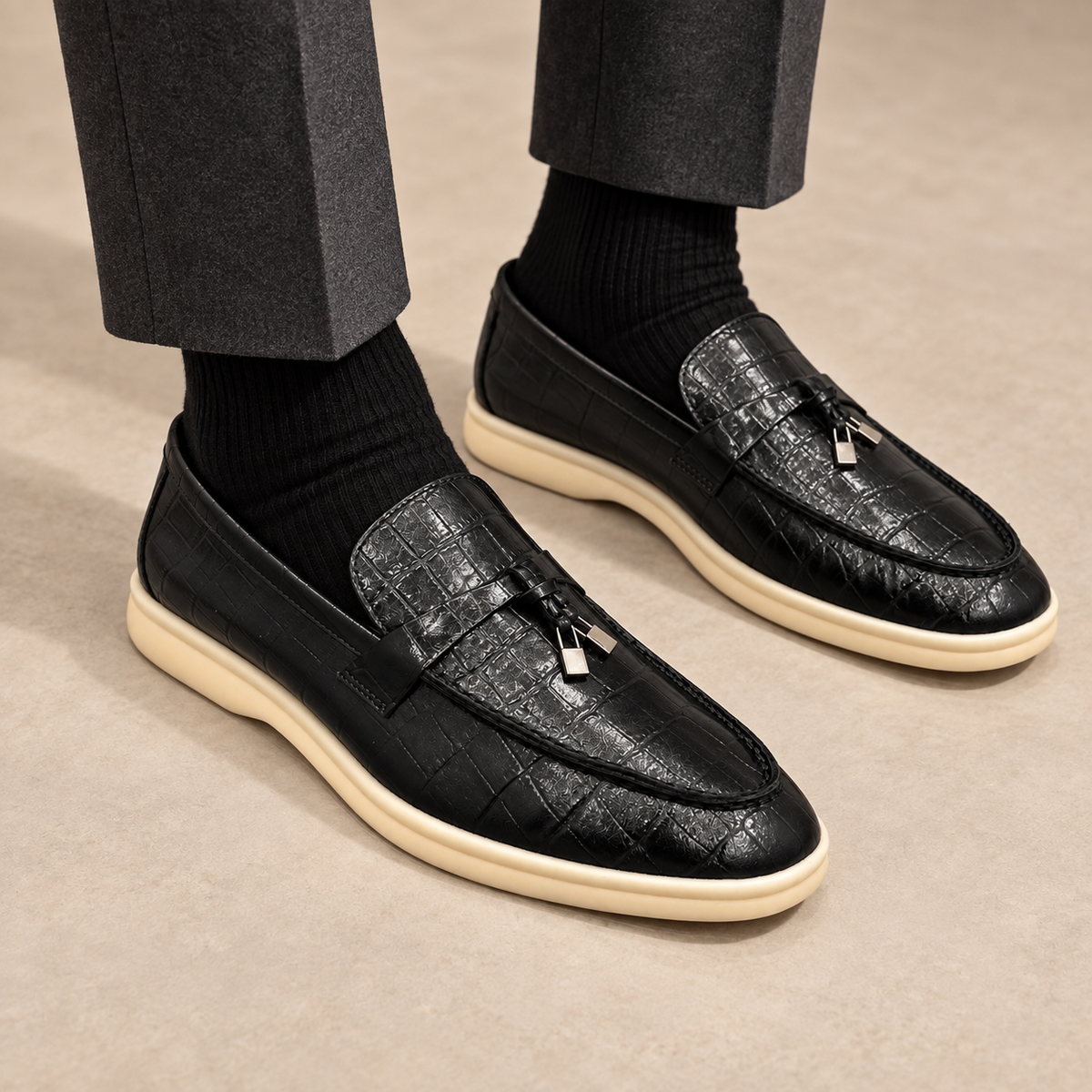 Black crocodile-embossed metal-accent loafers worn with charcoal trousers and black socks