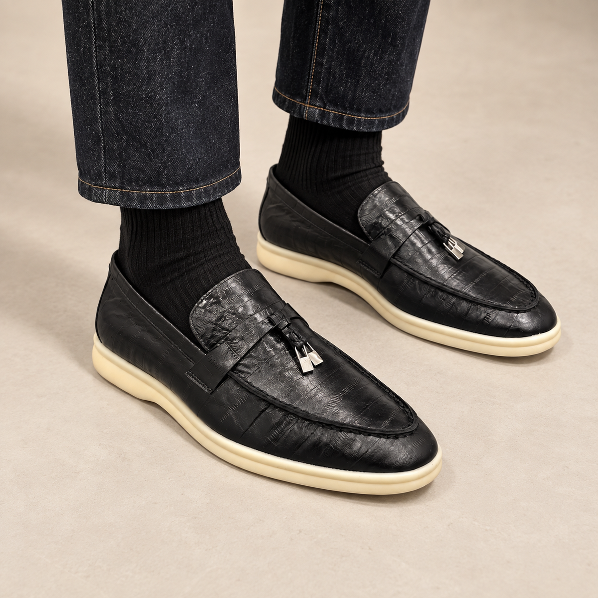 Black eel-embossed tassel loafers worn with dark denim and black socks