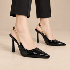 Black patent pointed-toe slingback pumps worn with black trousers