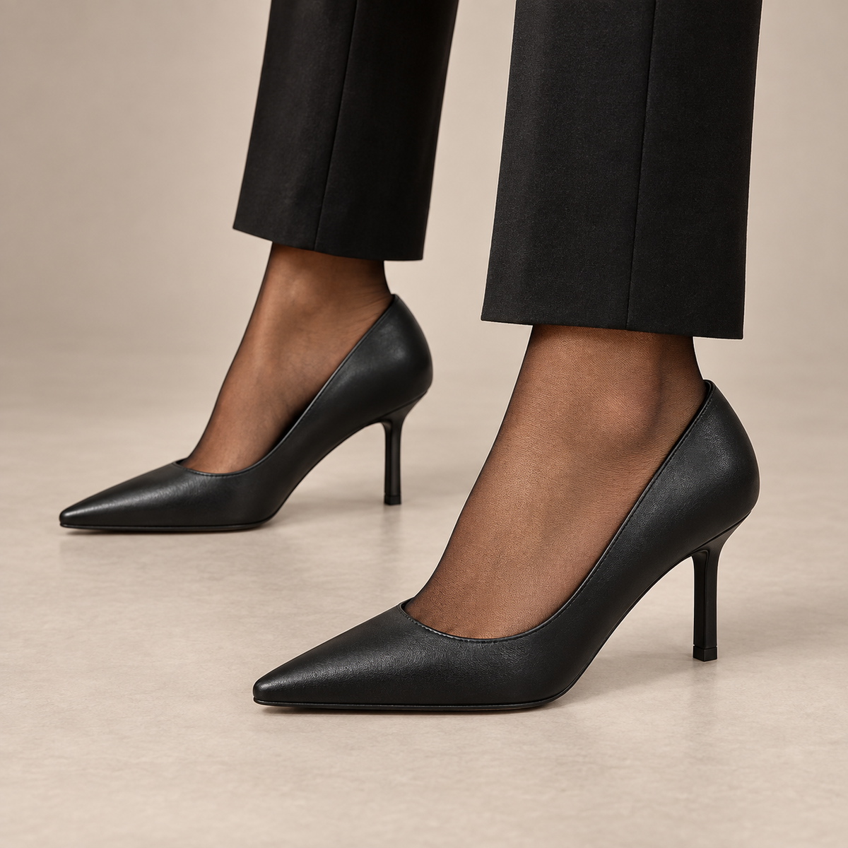 Black pointed-toe leather pumps worn with black trousers