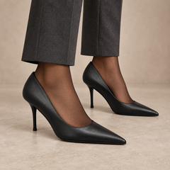 Black pointed-toe leather pumps worn with charcoal trousers