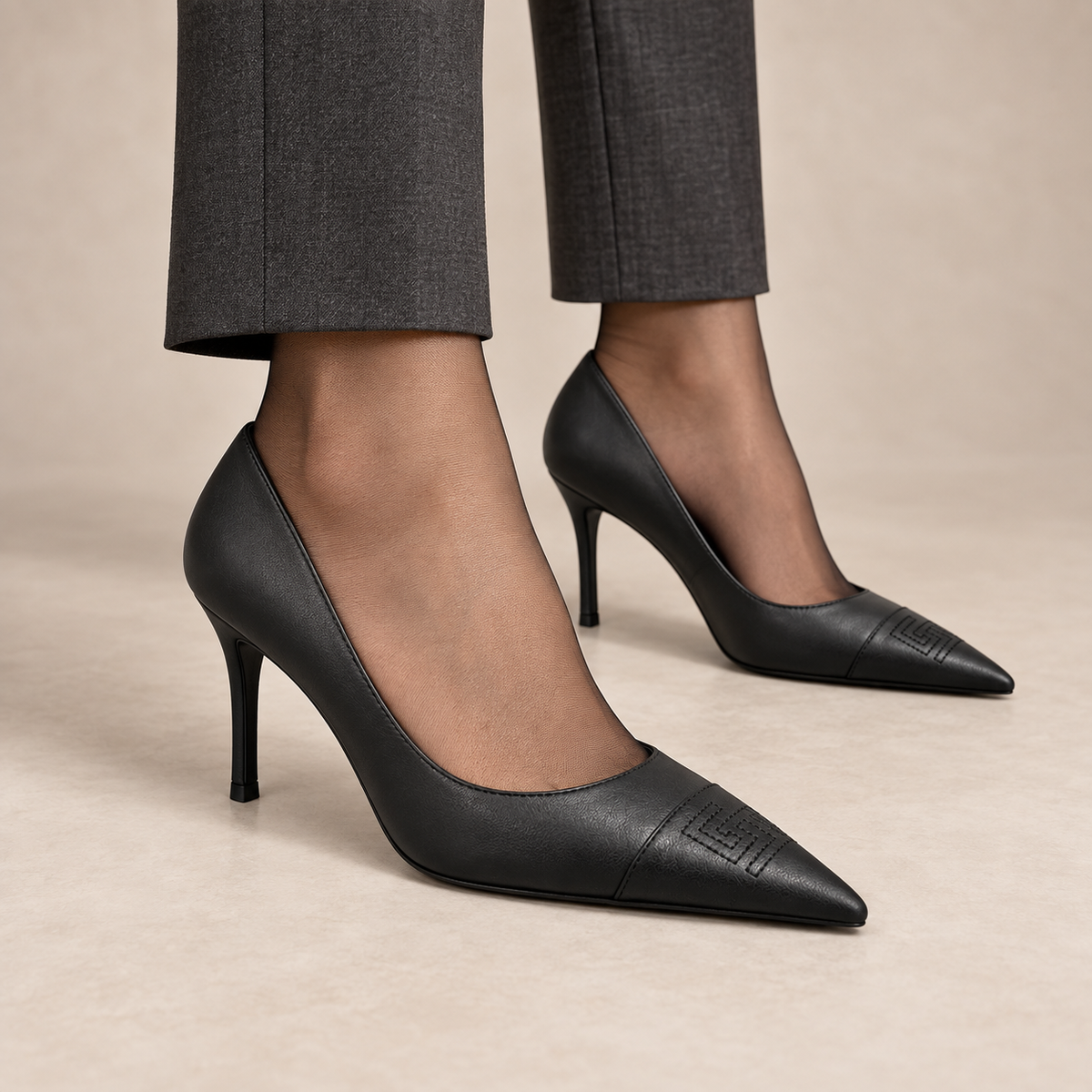 Black pointed-toe leather pumps worn with charcoal trousers