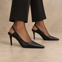 Black pointed-toe leather slingback pumps worn with black trousers