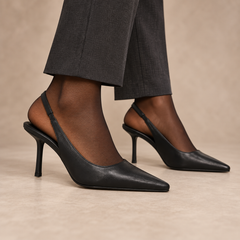 Black pointed-toe leather slingback pumps worn with charcoal trousers