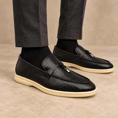 Black snakeskin-embossed tassel loafers worn with charcoal trousers and black socks