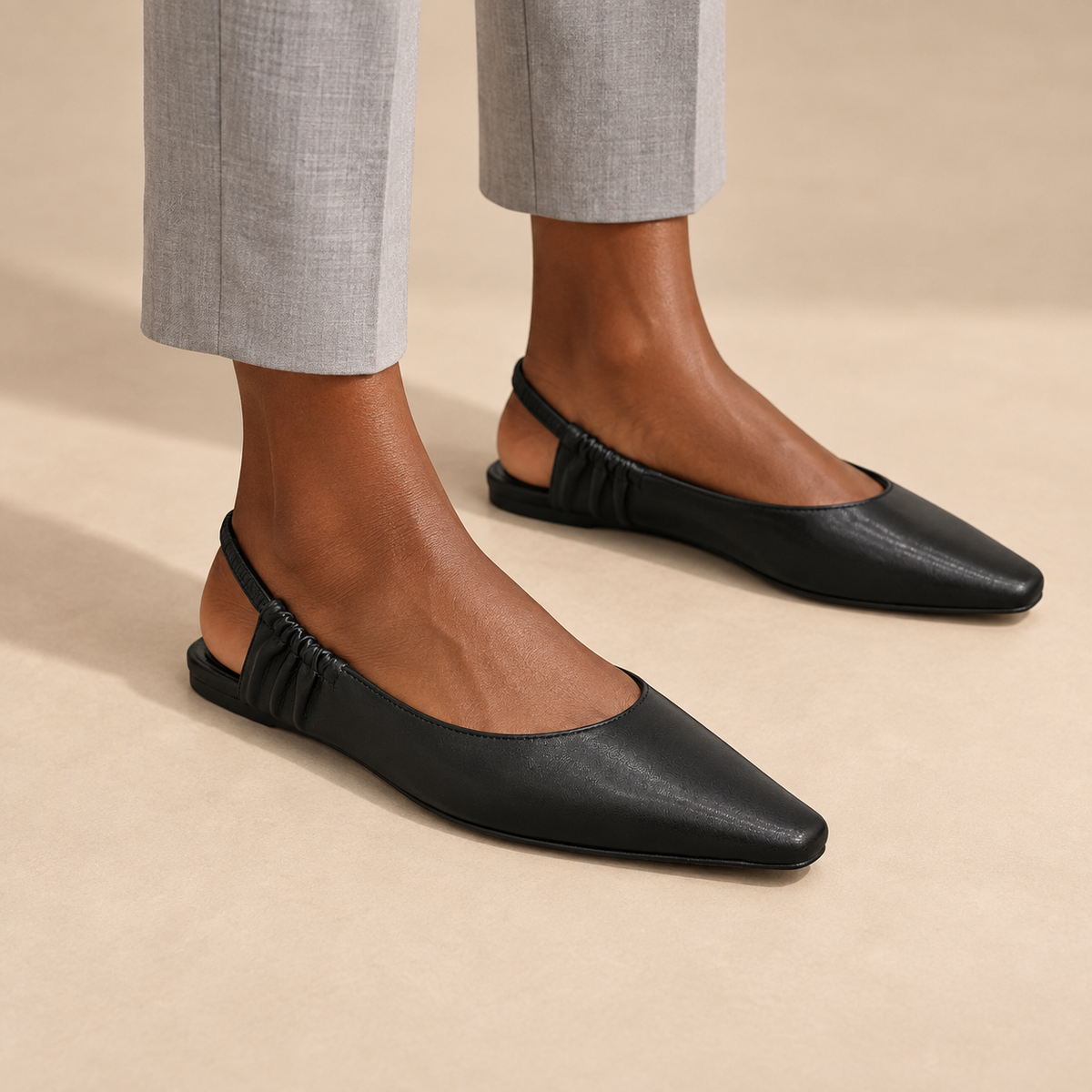 Black square-toe gathered-strap slingback flats worn with gray cropped trousers