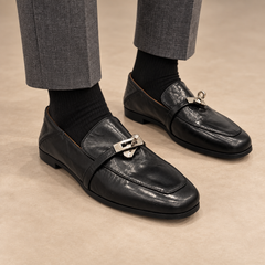 Black washed horse leather metal-accent loafers worn with gray trousers and black socks