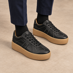 Black washed horse leather platform sneakers worn with navy trousers and black socks