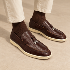 Brown eel-embossed tassel loafers worn with cream chinos and brown socks