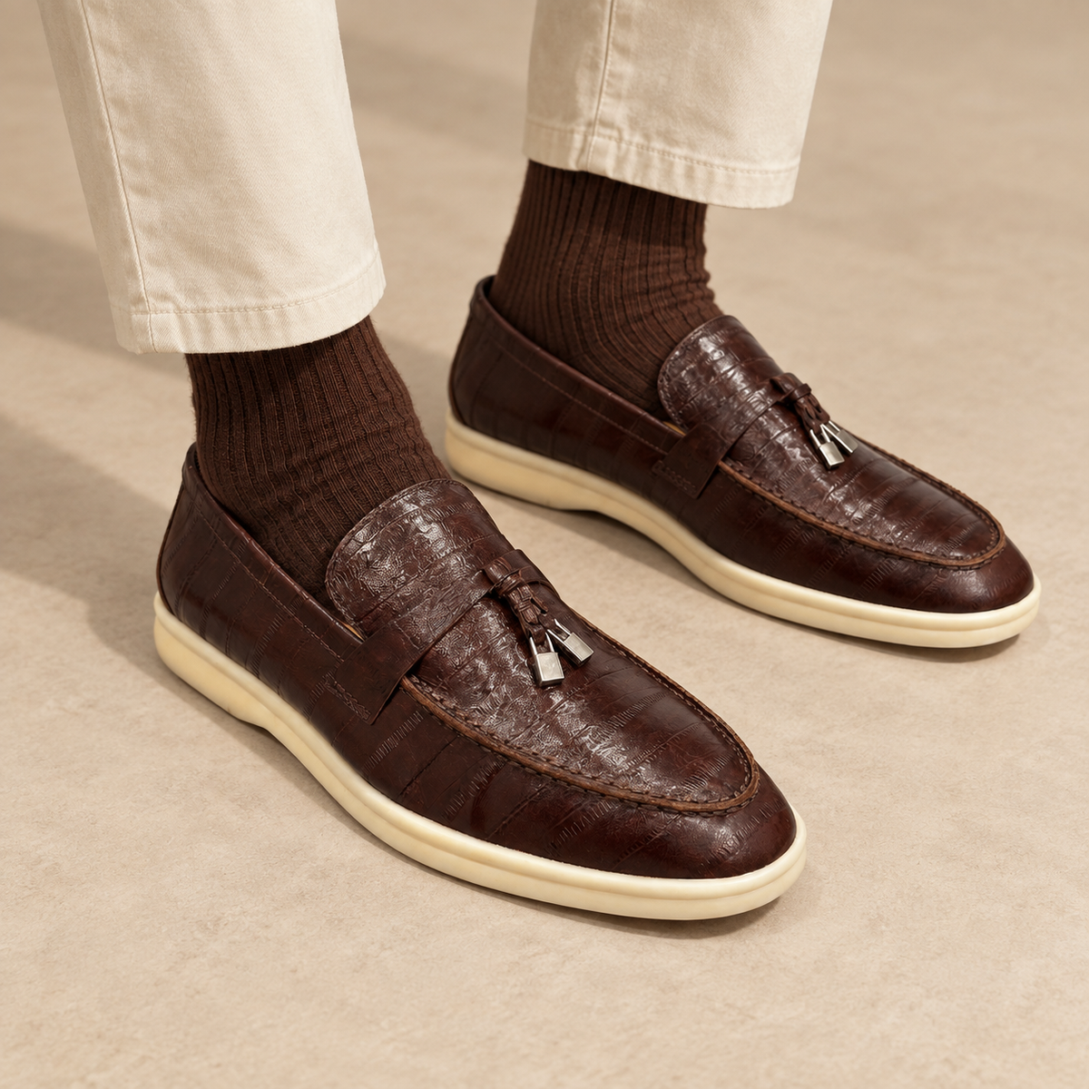 Brown eel-embossed tassel loafers worn with cream chinos and brown socks