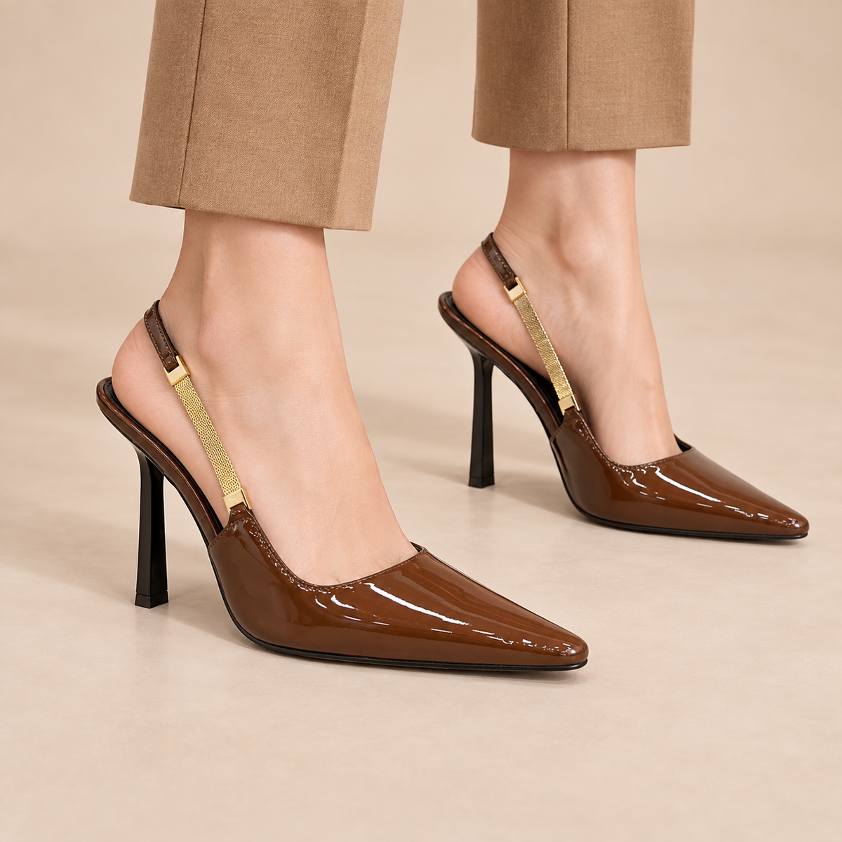 Brown patent pointed-toe slingback pumps worn with camel trousers