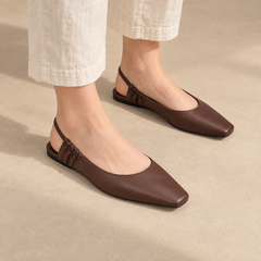Brown square-toe gathered-strap slingback flats worn with cream linen trousers
