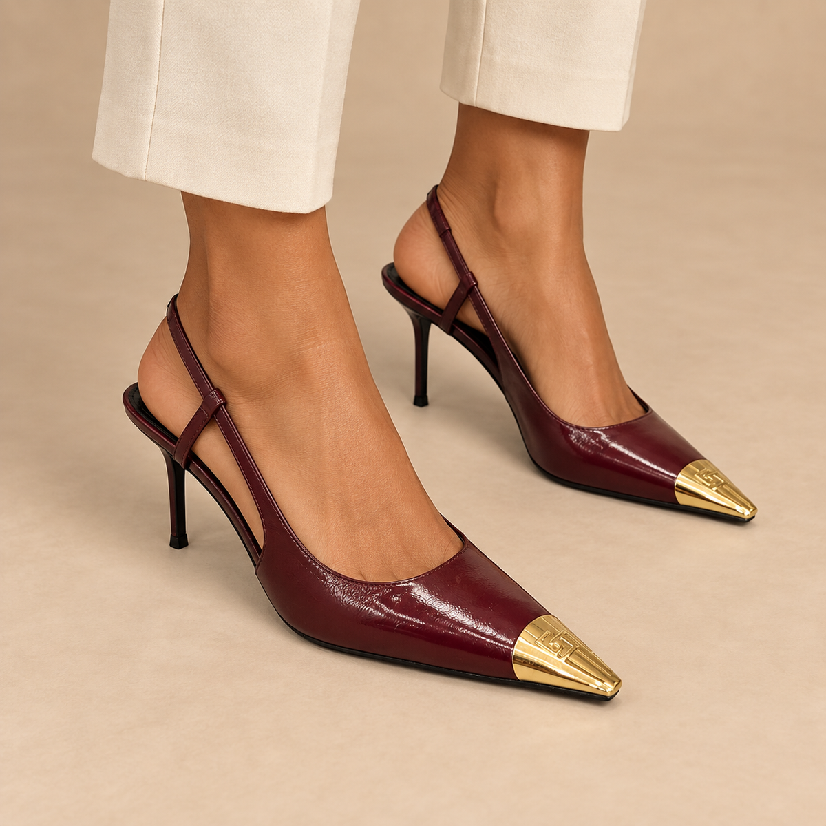 Burgundy pointed-toe metal-cap slingback pumps worn with cream trousers