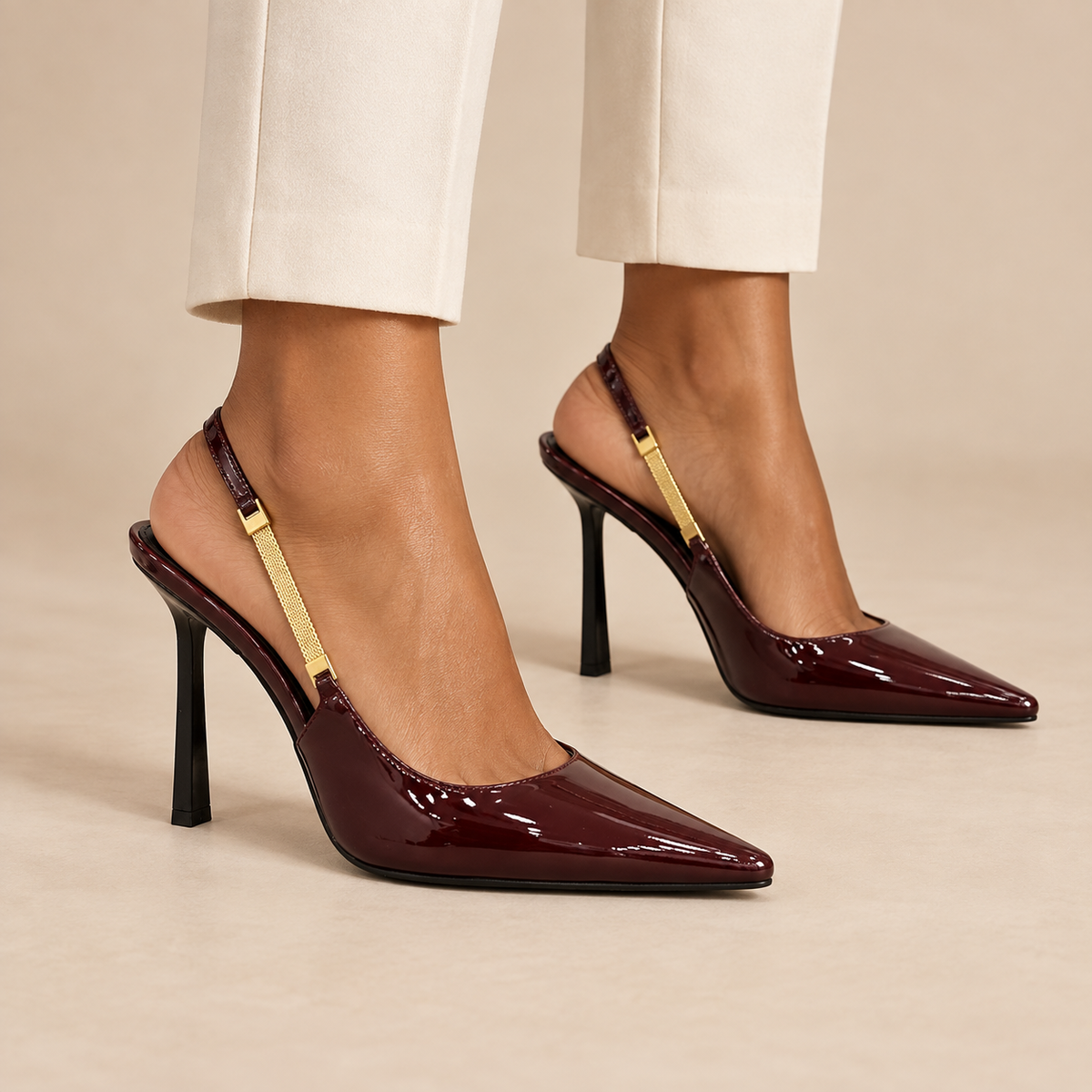 Burgundy patent pointed-toe slingback pumps worn with ivory trousers