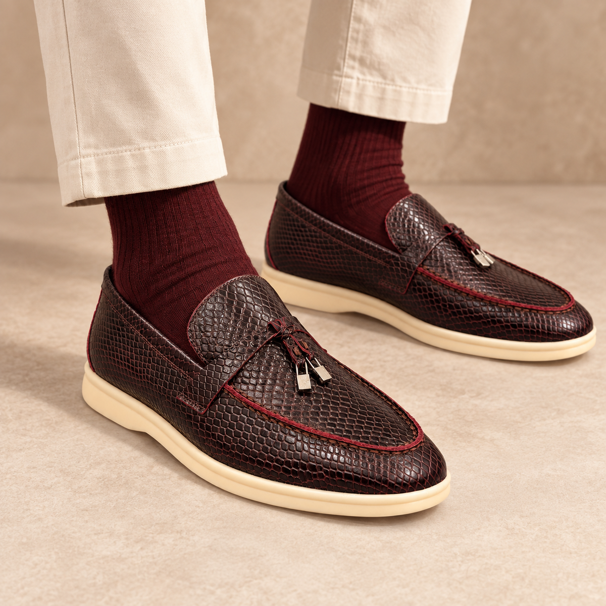 Burgundy snakeskin-embossed tassel loafers worn with cream cropped chinos and burgundy socks