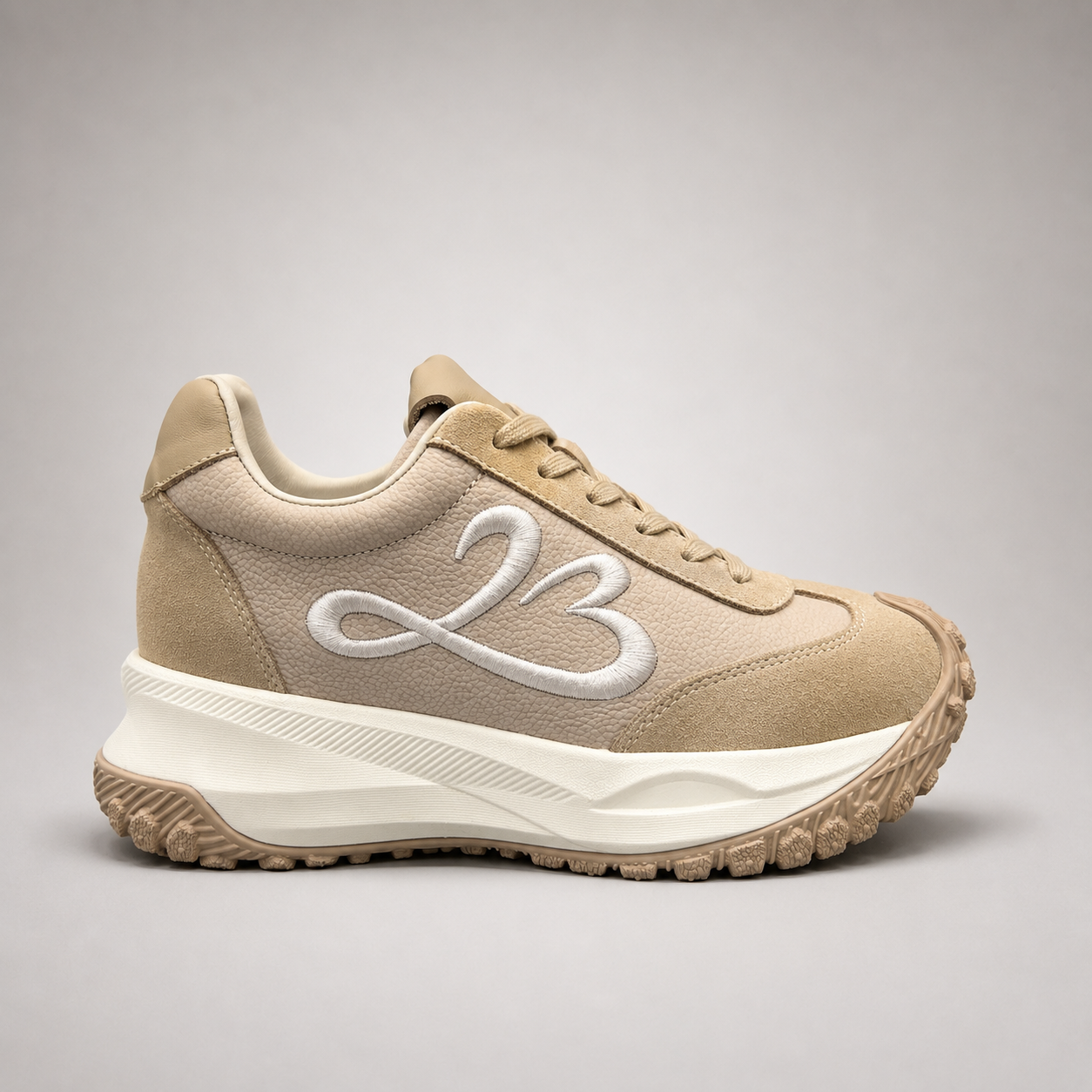 Beige sneaker side profile showing a panelled lace-up upper