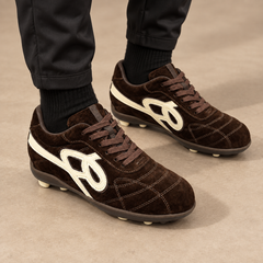 Dark-brown suede studded lace-up soccer shoes worn with black athletic trousers and socks