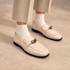 Ivory washed horse leather metal-accent loafers worn with beige trousers and ivory socks