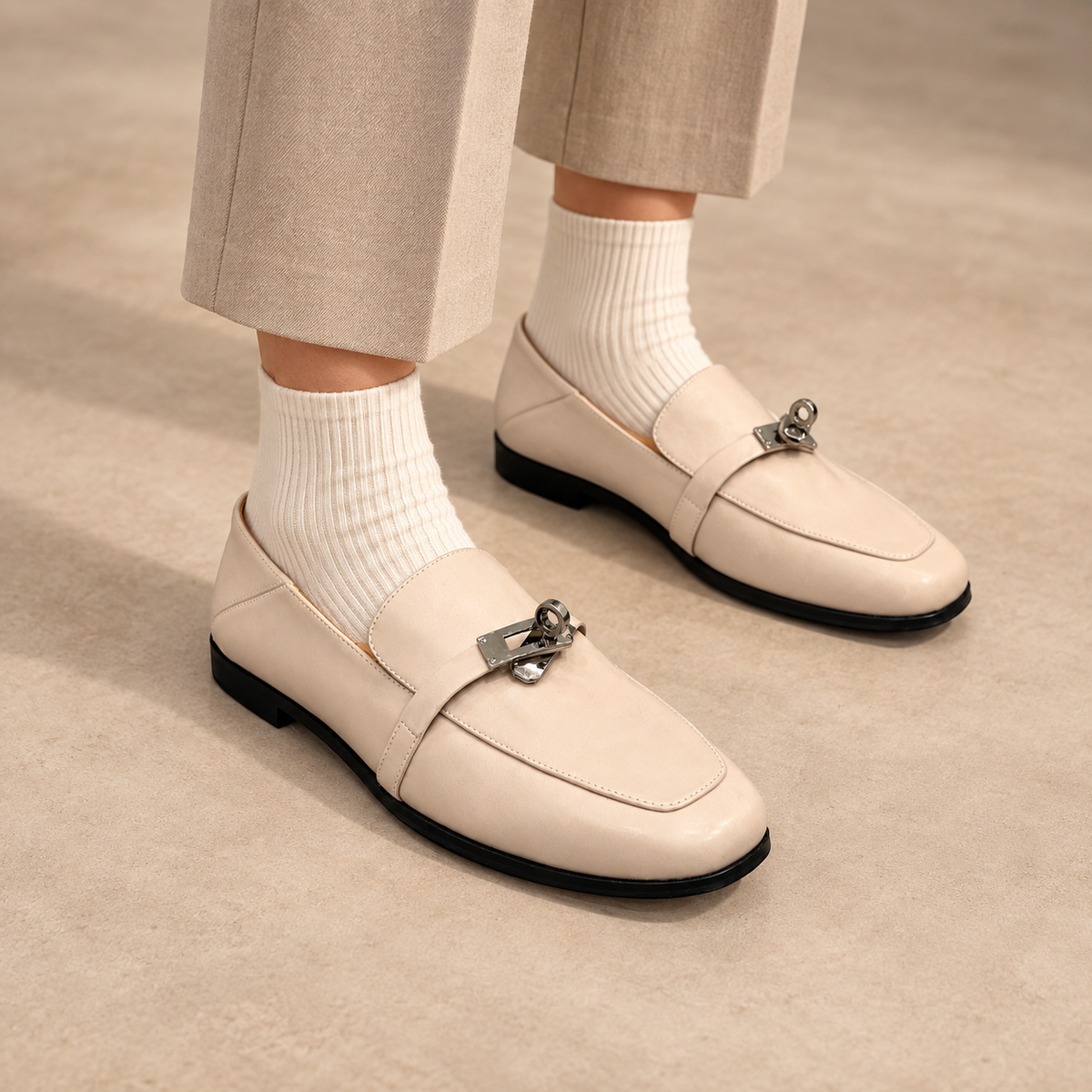 Ivory washed horse leather metal-accent loafers worn with beige trousers and ivory socks