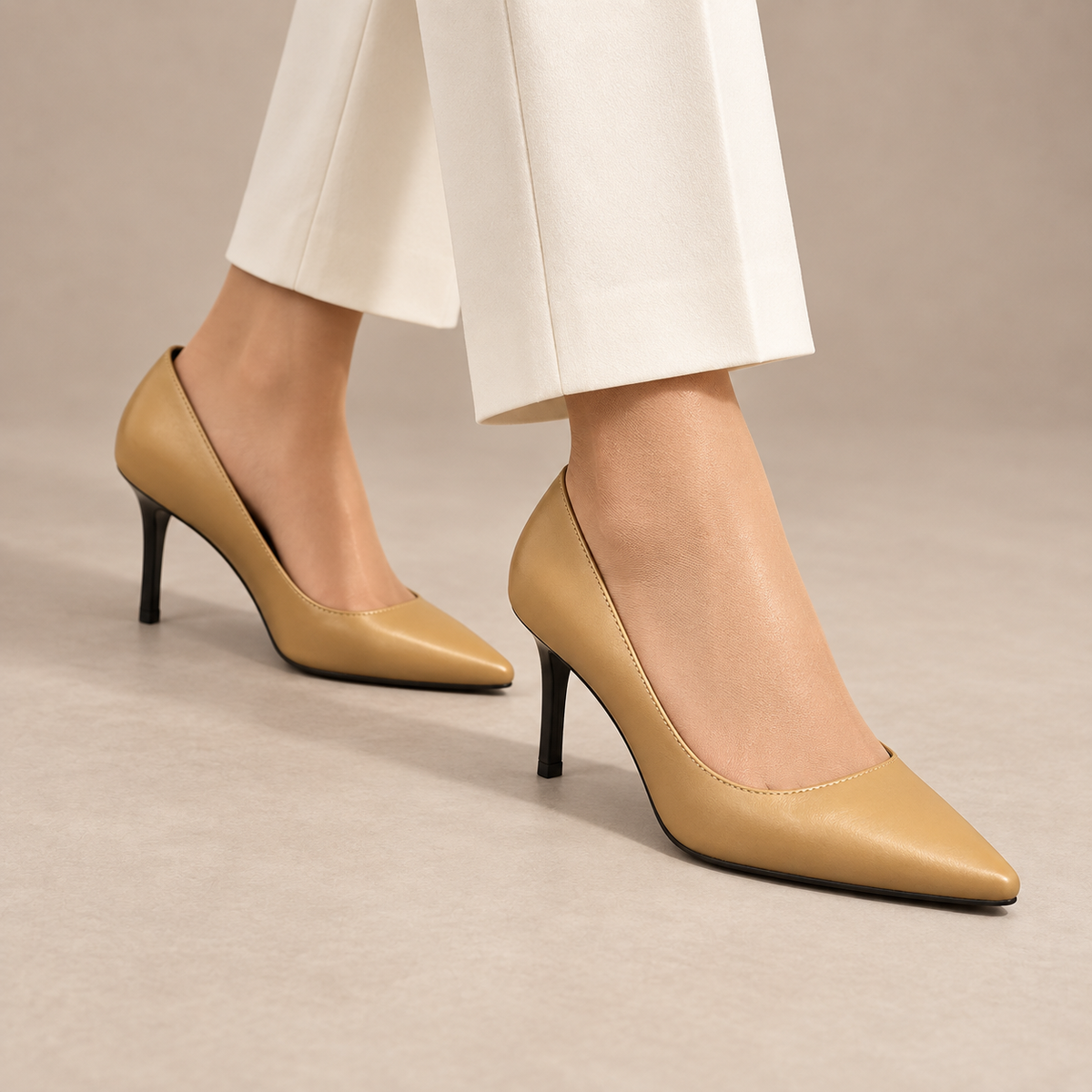 Tan pointed-toe leather pumps worn with ivory trousers