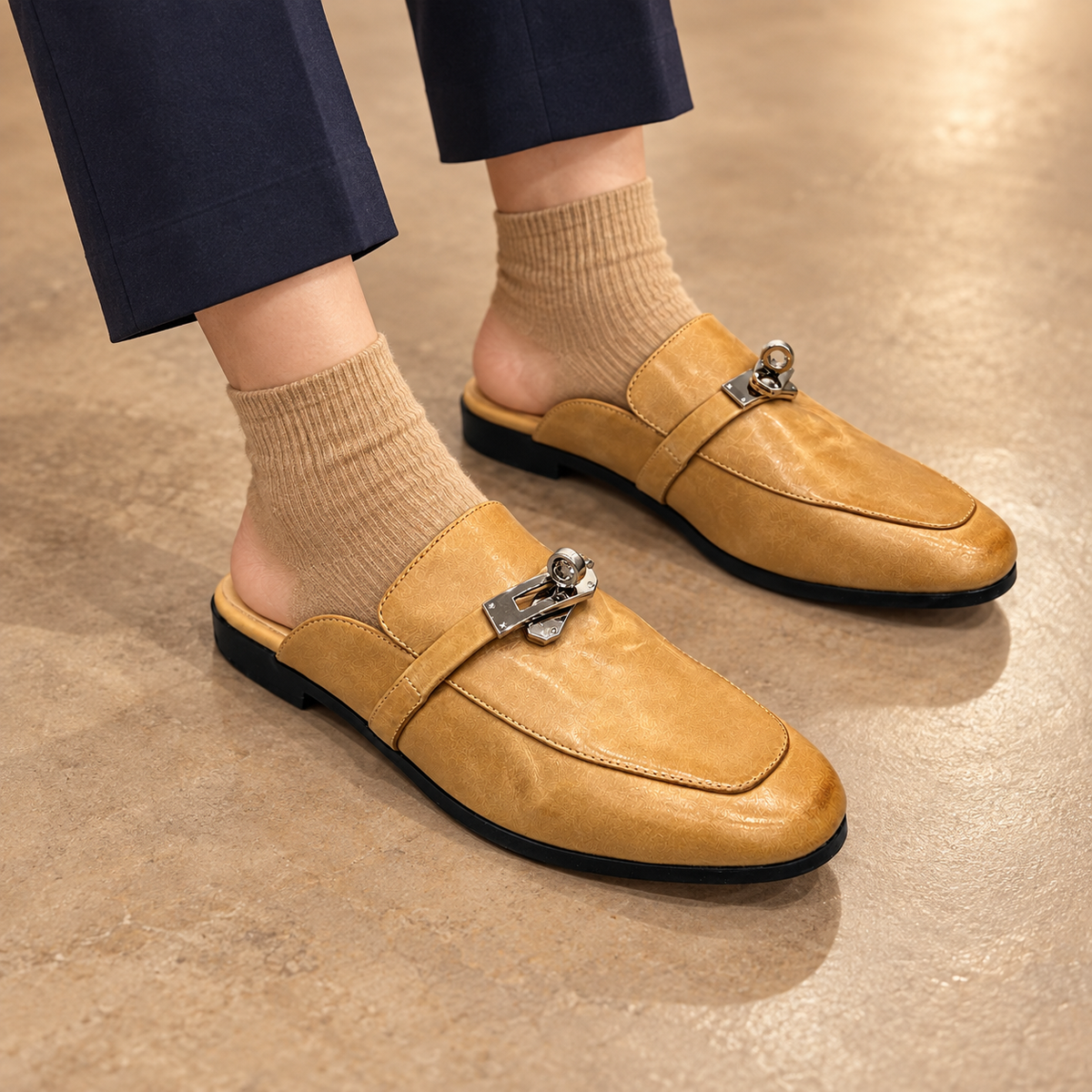 Tan washed horse leather metal-accent mule loafers worn with navy trousers and tan socks