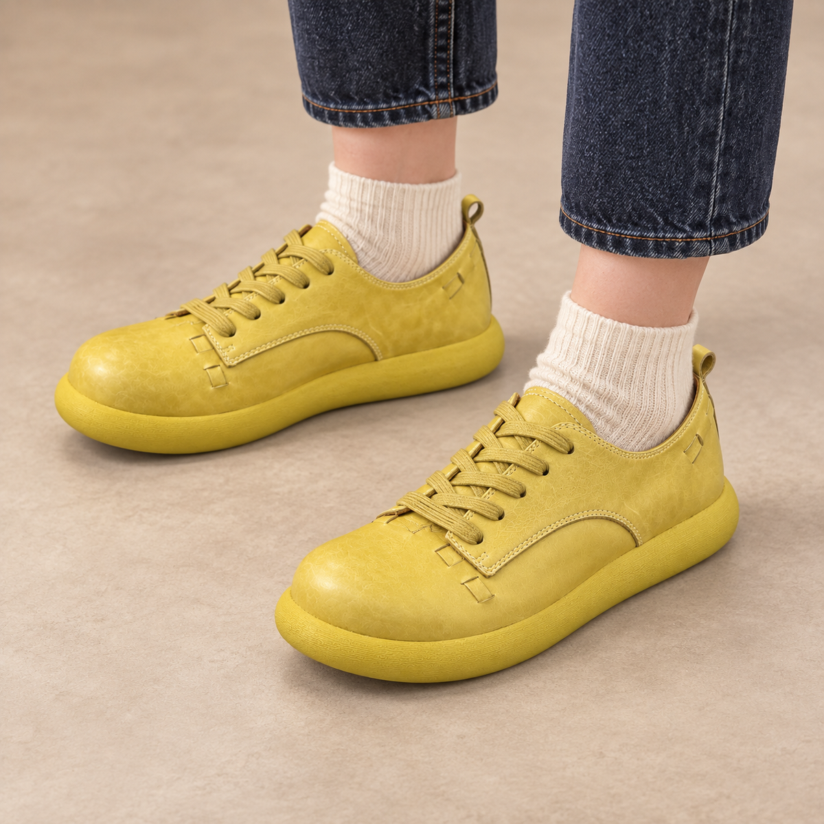 Yellow washed horse leather low-top sneakers worn with dark denim and cream socks